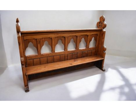 A 19th Century pitch pine church pew with low seat above gothic style gallery back rest and top rest, with gothic style end s