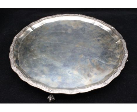 A George V silver salver, of curved circular shape with Celtic style cast border, on four claw and ball feet, hallmarked by W