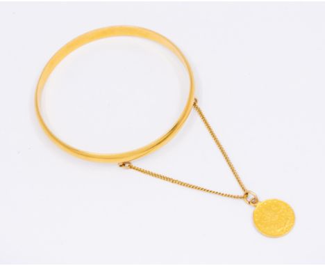 A yellow metal D section bangle, width approx 7mm,  internal diameter approx 68mm, unmarked assessed 21ct, suspending a Turki