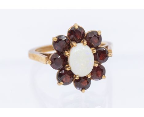 An opal and garnet 9ct gold mounted cluster ring, set with an oval opal within a border of round mixed cut garnets, setting a
