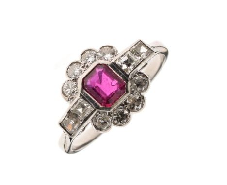 Ruby and diamond cluster ring, stamped 'Platinum', the step cut ruby enclosed by eight brilliant cuts with pairs of square cu