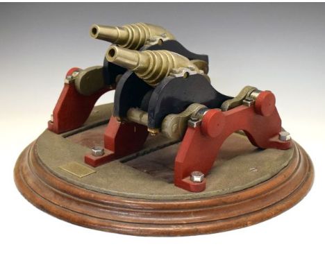 Pair of model coastal defence guns mounted together on movable carriages, when one raises, one retreats, each muzzle loading 