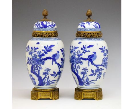 Pair of Chinese porcelain ovoid vases and covers, each decorated in underglaze blue with birds perching on blossoming trees, 