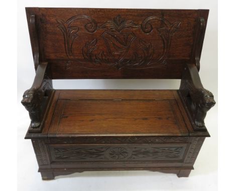 A 20th century oak monk's bench, with craved lion arms and carved back, 98cm long, 99cm long, 41cm deep  