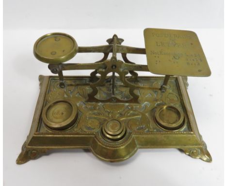A set of cast brass Edwardian postal scales, the rectangular base with scrolling folige decoration, and with set of brass sta