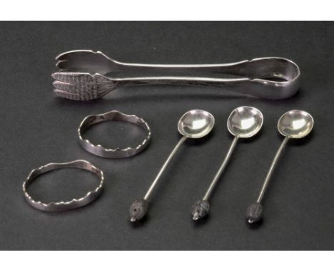 A pair of serving tongs, detailed sterling, makers mark rubbed, with foliate engraved three finger hand terminals, 16cm long,