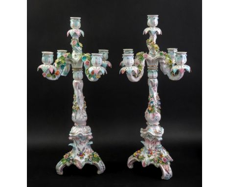 A pair of Sitzendorf five light candelabra, circa 1900, each painted and encrusted with flowers beneath four scroll arm branc