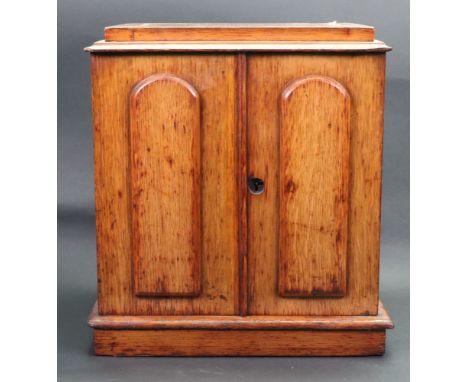 A Victorian light oak table top cigar cabinet, circa 1880, fitted with three drawers enclosed by a pair of raised arched pane