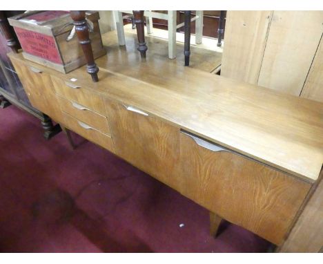 A 1960s teak long sideboard, having three centre drawers, single fall-front compartment (with damage to hinges), flanked by e