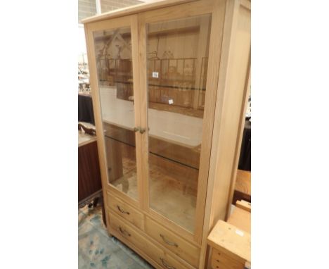 Light oak display cabinet with three drawers below 