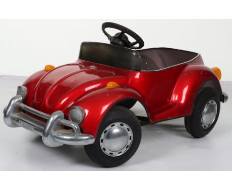 A pressed steel child’s VW Beetle pedal car, probably English circa 1970, painted in metallic red with black padded seat, bla