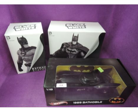 A HotWheels 1:18 scale diecast model, 1989 BatMobile along with two DC Collectibles BatMan Statues, all appear unopened and b