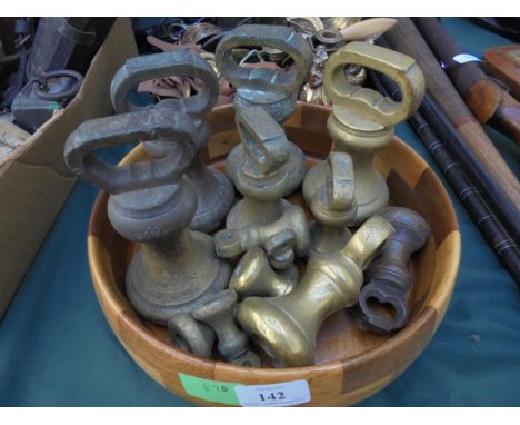 Circular wooden bowl containing large amounts of heavy brass weights from weighing scales 