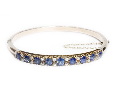 A Victorian sapphire and diamond bangle, the nine oval cut sapphires measuring approximately 4mm x 3.75mm to 5.45mm x 4.45mm,