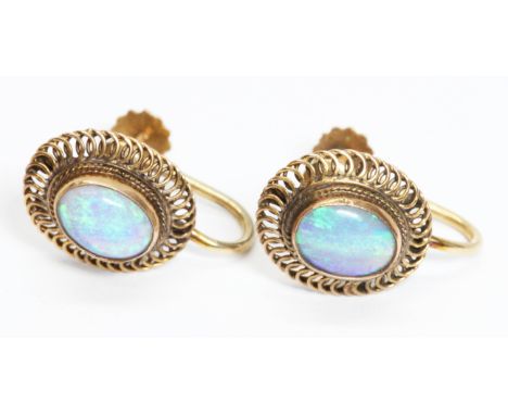 A pair of opal cabochon earrings, filigree border, screw backs marked '14K', head measuring 11mm x 13mm, gross weight 3.1g.  