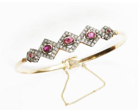 A ruby and diamond bangle, the cluster measuring approximately 47mm x 6mm, band marked '585', diameter 55mm, gross weight 12.