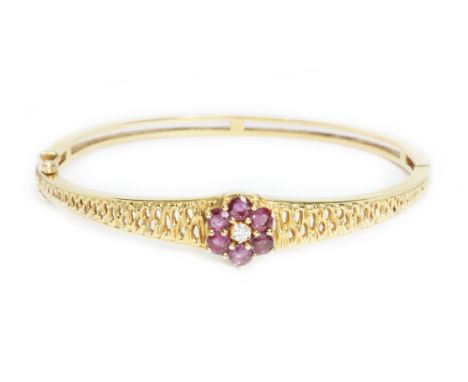 A diamond and ruby bangle, the cluster measuring approximately 12mm in diameter, yellow metal marked '750', inner diameter ap