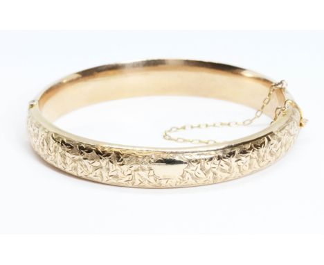 An Edwardian 9ct gold bangle, engraved front design, hallmarked; sponsor 'JGG', Birmingham 1910, diameter 5cm, weight 11.3g. 