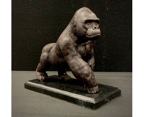 A bronzed metal model of a gorilla on black marble plinth, 20cm long 