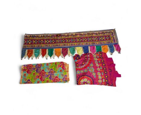 A large Indian silk embroidered and mirrored temple pelmet, with a cerise silk embroidered hanging and a length of cotton wax