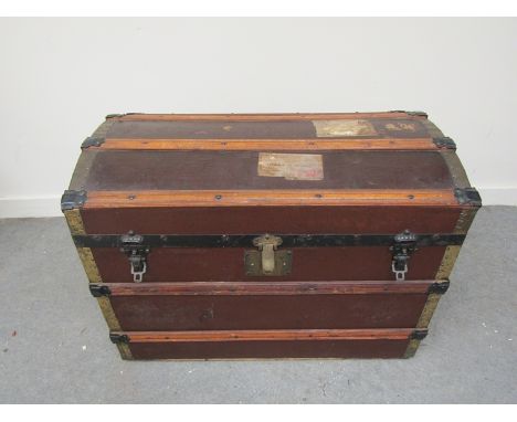 An Edwardian domed top luggage trunk with hard canvas body, wooden bound supports. Cast iron and brass fixings, lined interio