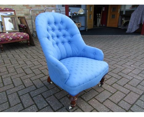 An early Victorian button back walnut armchair with blue upholstery on turned legs and white ceramic castors