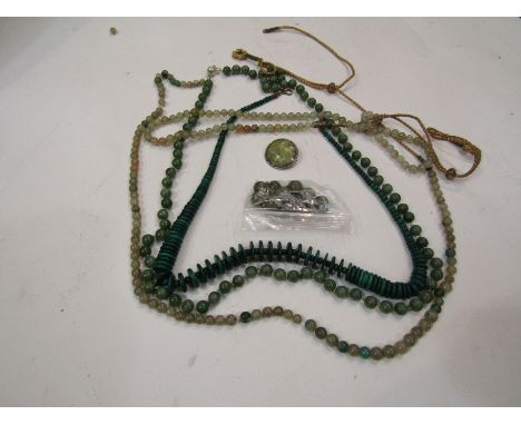 A collection of turquoise, jade and malachite-coloured bead necklaces.  A polished green agate cabochon in a brooch mount   
