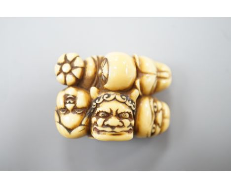A Japanese ivory netsuke of a Daruma doll and four noh masks, signed, 19th century, 3.8cm