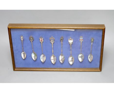 A collection of sixty four 800 standard silver (many gilt) and enamel souvenir spoons, early 20th century, in eight display c