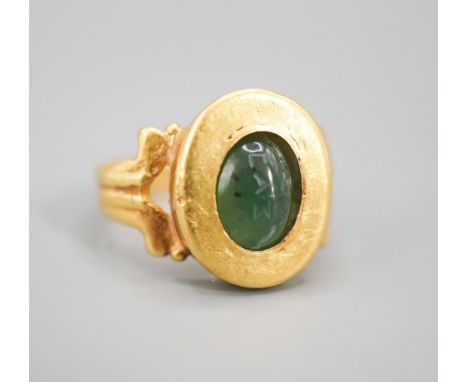 An antique yellow metal and carved nephrite? oval ring, size H, gross 4 grams (the stone is loose in situ and needs re-settin