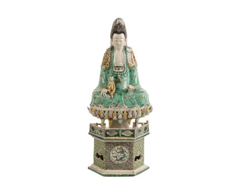 FAMILLE VERTE SEATED GUANYIN, KANGXI PERIOD, modelled seated with an acolyte resting on one knee, on an overlapping petal sta