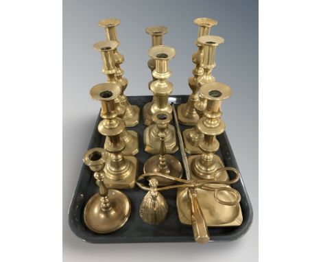 Five pairs of brass candlesticks, fire poker, pair of tongs, figural bell and an ashtray.