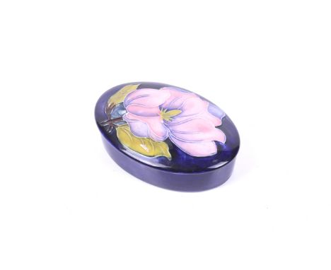 A 20th century Moorcroft trinket dish. Of oval form, having tubelined floral decoration featuring a pink flower on a blue gla