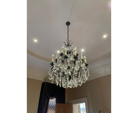 A contemporary metal framed chandelier, Having three tiers, the upper tier with eight branches all suspended with glass dropl