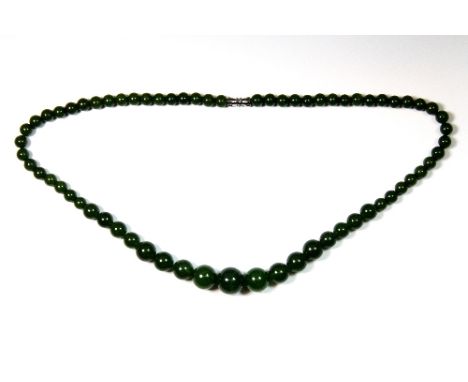 A graduated single row necklace of green jade beads