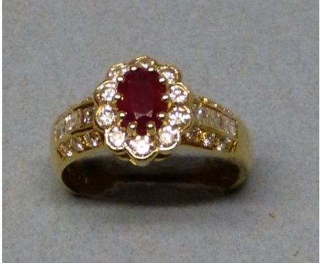 An 18ct gold, ruby and diamond cluster ring, claw set with an oval mixed cut stone of approximately 0.80cts, bordered by ten 