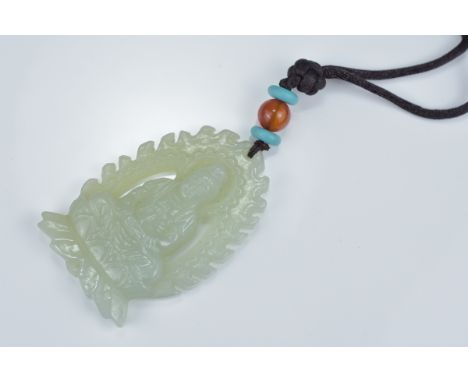 A Chinese carved pale celadon jade pendant carved as a seated Buddha on lotus stand. 5.5cm length
