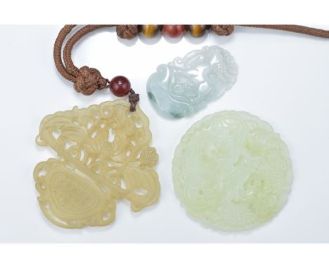 A Chinese carved jadeite deer pendant together with a pale celadon jade dragon pendant and one other jade pendant carved as a