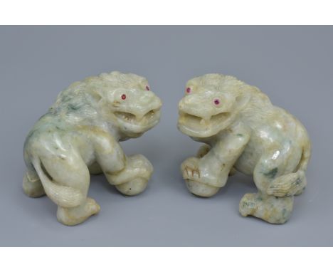 A pair of 19th century carved jadeite lions possibly Asian with ruby stone inserts in the eyes. 9Cm length (2)