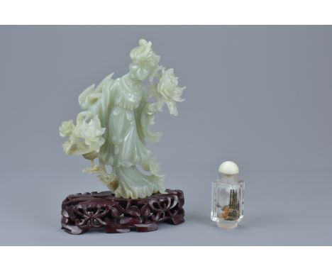 A Chinese jade figure of a Goddess holding flowers on a carved wooden stand together with a small reverse glass painted bottl