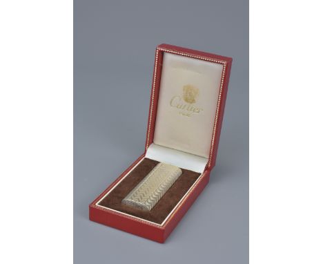 A Cartier Paris silver-plated lighter in original display box. Serial number 34584 A. 7Cm length.