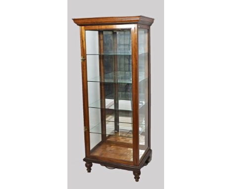 Vitrine. Dreiseitig verglastes Nussbaumgestell mit Fronttür. Auf Balusterfüßen. Innen mit drei Glasböden und verspiegelter Rü