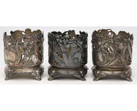 Drei Jugendstil-Flaschenhalter, WMF. Britannia, versilbert. Profilierter, runder Sockel auf vier Füßen. Zylindrische Wandung 
