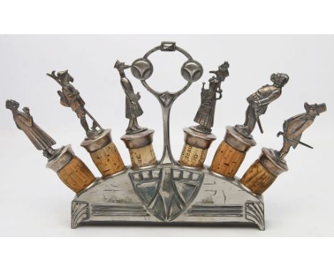 Jugendstil-Flaschenkorkengarnitur im Ständer, WMF. Britannia, versilbert. Die Korkenaufsätze als karikierende, vermenschlicht