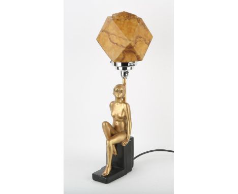 Art Deco gilt decorated and black painted plaster table lamp, the woman seated on a stepped base, the facetted glass shade wi