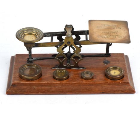 A set of Mordant & Co. London brass postal scales, together with six weights, four inset and two loose, on an oak base, the t