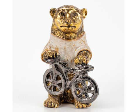 A ceramic figurine of a bear with bicycle, with gold and white glaze. Around 1970. (12 x 10 x 20 cm)