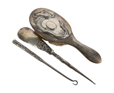 A Chinese silver-backed clothes brush, with embossed dragon decoration, a Chinese silver combination button hook/shoe horn, a