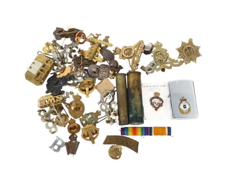 A collection of military badges, bullet cases, and a Japanese lighter with an applied Royal Canadian Airforce badge to the fr