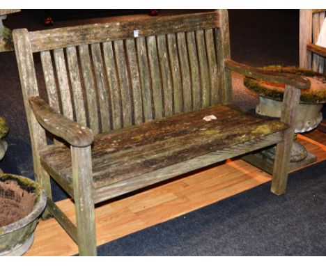 A wooden garden bench, with shaped arm rests, raised on block supports, 94cm high x 130cm wide x 63cm deep